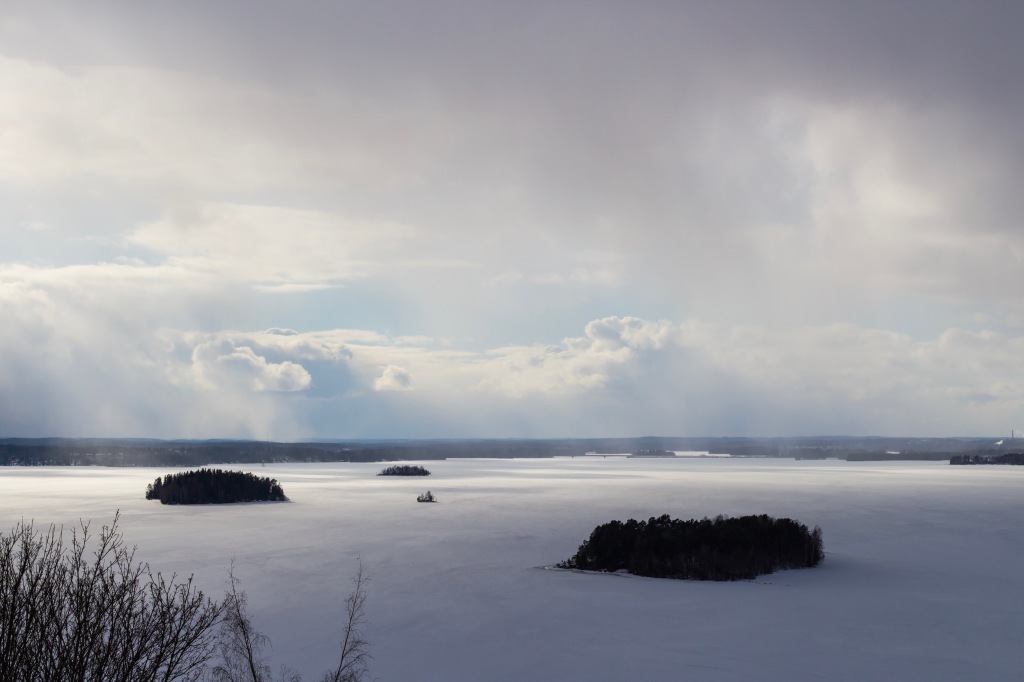 Thick clouds above an icy lake, sunlight coming through in distance